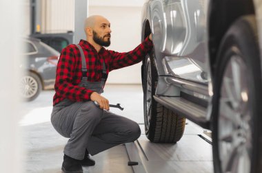 Tamirci tamirhanede araba bakımı için İngiliz anahtarı tutuyor ve çalışıyor.