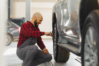 Atölyedeki arabanın yanında İngiliz anahtarı olan bir araba tamircisinin eli.
