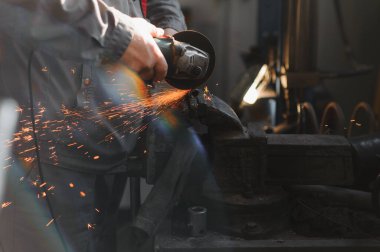 Öğütücüyle metal kesen bir işçi. Demir öğütürken kıvılcımlar