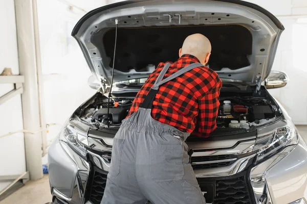 Mechanic working and holding wrench of service order for maintaining car at the repair shop