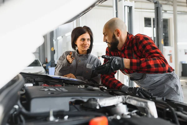 auto service, repair, maintenance and people concept - mechanic men with wrench repairing car engine at workshop