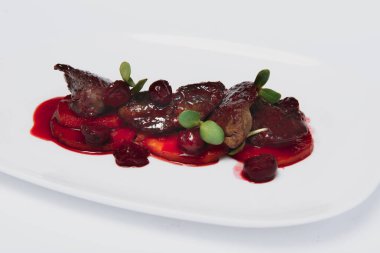 Taze bitki ve kiraz soslu et, beyaz arka planda yemeye hazır.