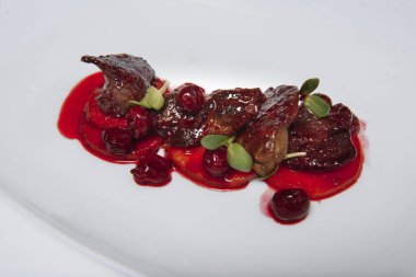 Taze bitki ve kiraz soslu et, beyaz arka planda yemeye hazır.