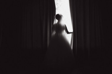 Beyaz ipek sabahlık güzel gelin portresi kıvırcık saç modeli ve peçe yatak odasında pencere yakınında duran, kopya alanı. Gelinin sabah hazırlığı. Geri görünüm