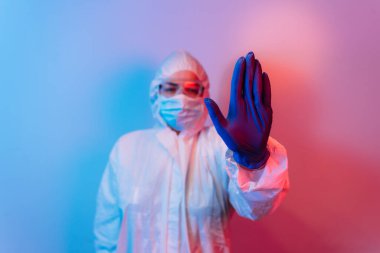 Koronavirüs. Koruyucu takım elbiseli kadın doktor ve gaz maskesi elinde dur işareti yapıyor. Koronavirüs