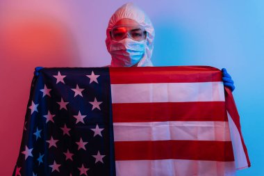 Birleşik Devletler 'i koronavirüs salgınından kurtar. COVID 19 koruyucu giysili doktor, maske ve eldivenli Amerikan bayrağı. Karantina konsepti.
