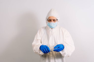 Mikrop ve virüslere karşı el dezenfektanı. Alkol içeriyor. Mavi eldiven giyen bir doktor elinde bir şişe tutuyor. Arka planda bulanık bir doktor var. Koronavirüsü durdurun. COVID-19.