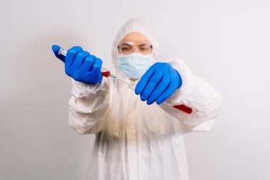 Doktorun elleri şırıngayı koronavirüs aşısıyla dolduruyor, iğneye hazırlanıyor. Covid-19 koruması. Salgın, salgın, aşı konsepti. Yeni aşıyı test ediyorum. Koruyucu kıyafetli doktor.