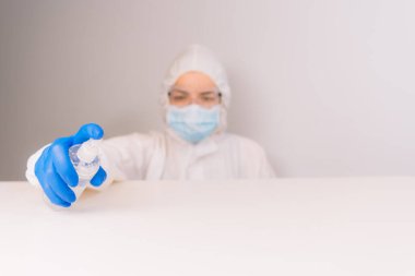 Koruyucu kıyafetli bir doktor antiseptikle dezenfekte ediyor. Coronavirus kontrol konsepti. Karantina.
