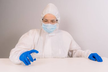 Koruyucu kıyafetli bir doktor antiseptikle dezenfekte ediyor. Coronavirus kontrol konsepti. Karantina.