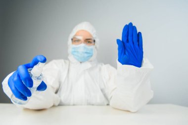 Koruyucu kıyafetli bir doktor antiseptikle dezenfekte ediyor. Coronavirus kontrol konsepti. Karantina.