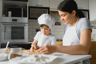 Mutlu anne ve çocuk mutfakta kurabiye hazırlıyor.