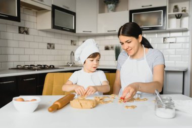 Genç anne ve küçük oğlu mutfakta yemek pişiriyor.