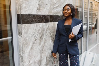 Endişeli yönetici dışarıda cep telefonuyla konuşuyor. Açık hava cam duvarının yanında duran genç Afrikalı Amerikalı iş kadını. Cep telefonu konuşma konsepti