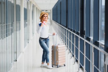 Yolculuk için hazırım. Pasaportu havaalanının arka planında elinde tutan kadın. Yüksek mevsim ve tatil konsepti. Rahatlayın ve yaşam tarzları