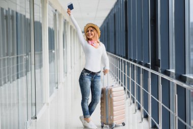 Havaalanı terminalinde bavuluyla yürüyen bir kadın, seyahat konsepti. Yüksek mevsim ve tatil konsepti. Rahatla ve yaşam tarzını değiştir. Seyahat ve Tatil Konsepti.