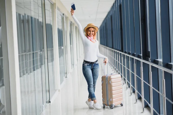 ready for the trip. Woman hold passport in hand with luggage on airport background. High season and vacation concept. Relax and lifestyles