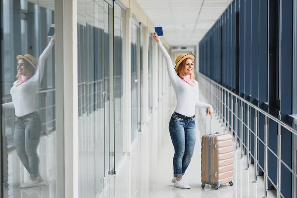 ready for the trip. Woman hold passport in hand with luggage on airport background. High season and vacation concept. Relax and lifestyles