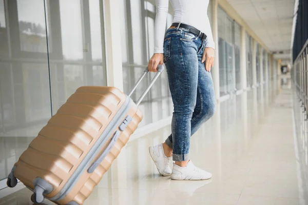 A woman with hand luggage walking in airport terminal