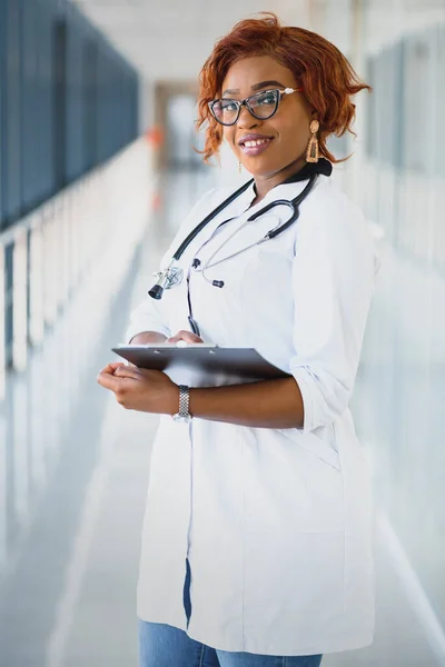 Pretty young African American medical professional standing and looking at camera in a hospital.
