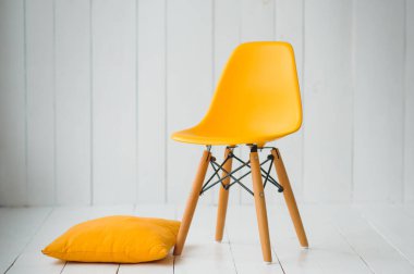 Beyaz bir duvarın arkasında sarı modern sandalyeler