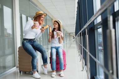 Uluslararası havaalanında küçük kızı olan bir kadın. Anne ve bebek uçuşlarını bekliyorlar. Çocuklarla seyahat etmek.