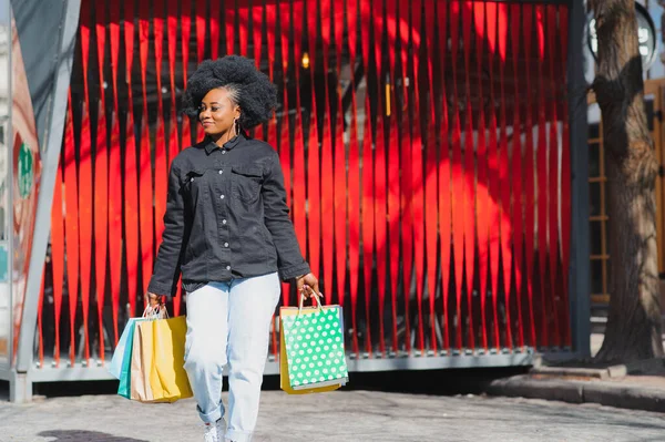 穿着红色背景的购物袋的非洲美女形象 — 图库照片