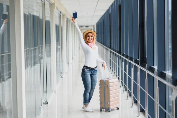 ready for the trip. Woman hold passport in hand with luggage on airport background. High season and vacation concept. Relax and lifestyles