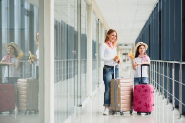 Uluslararası havaalanında küçük kızı olan bir kadın. Anne ve bebek uçuşlarını bekliyorlar. Annesiyle muz yiyen kızı. Çocuklarla seyahat etmek.