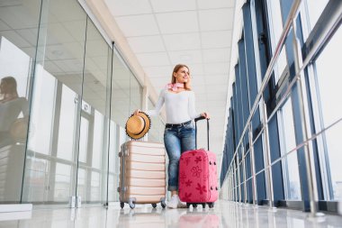 Havaalanı terminalinde bavuluyla yürüyen bir kadın, seyahat konsepti. Yüksek mevsim ve tatil konsepti. Rahatla ve yaşam tarzını değiştir. Seyahat ve Tatil Konsepti.