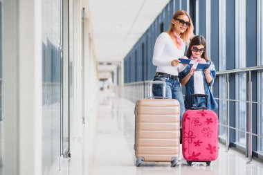 Güzel bir anne ve kızın elinde pasaportları ve havaalanından biniş kartı var.