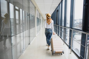 Havaalanı terminalinde bavuluyla yürüyen bir kadın, seyahat konsepti. Yüksek mevsim ve tatil konsepti. Rahatla ve yaşam tarzını değiştir. Seyahat ve Tatil Konsepti.
