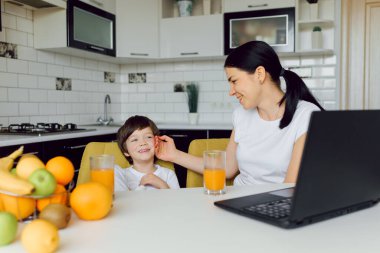 Sağlıklı beslenme, aile ve insan konsepti - mutlu anne ve oğul ev mutfağındaki tablet bilgisayarda online tarifle akşam yemeği için sebze pişiriyorlar.