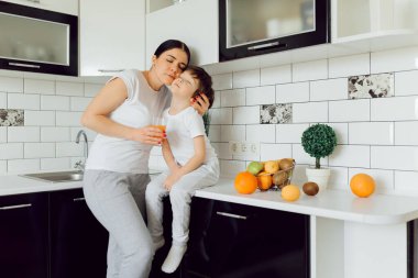 Küçük çocuk ve anne meyvelerle oynuyorlar ve oynuyorlar. Tişört giyiyorlar.