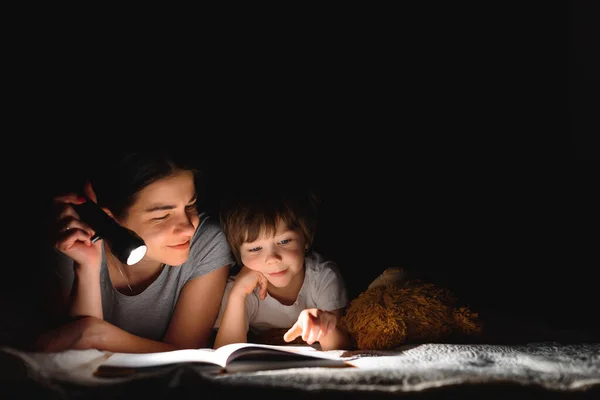 快乐的家庭故事的时间到了快乐快乐可爱的母亲和儿子在睡觉前 用手电筒欣赏着一本书 — 图库照片