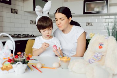 Anne ve oğlu Paskalya yumurtası boyuyor. Mutlu aile Paskalya için hazırlanıyor..