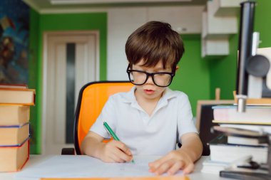 Çocuk evde CoVid-19 karantinası sırasında ders çalışıyor, uzaktan öğrenmeyi bilgisayarla öğreniyor, çocuk okul için ödev yapıyor. Okul çocuğu evde kaldı..