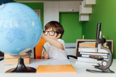 Çocuk evde ödev yapıyor. Çocuklar çalışır ve öğrenir. Anaokulu çocuğu yazıp okuyor. Okula geri dön..