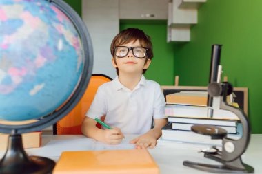 Çocuk evde ödev yapıyor. Çocuklar çalışır ve öğrenir. Anaokulu çocuğu yazıp okuyor. Okula geri dön..