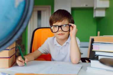 The boy is studying at home during CoVid-19 quarantine, distance learning online with a laptop, the child is doing homework for school. The schoolboy stayed at home. clipart