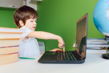 Çocuk evde CoVid-19 karantinası sırasında ders çalışıyor, uzaktan öğrenmeyi bilgisayarla öğreniyor, çocuk okul için ödev yapıyor. Okul çocuğu evde kaldı..