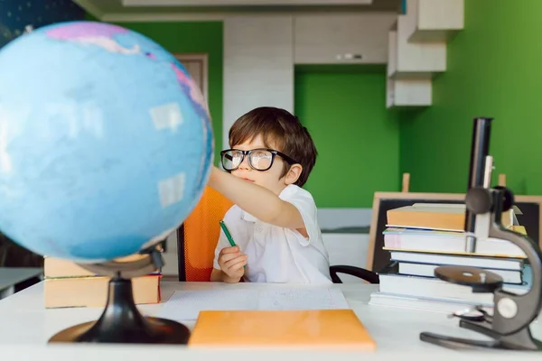 The boy is studying at home during CoVid-19 quarantine, distance learning online with a laptop, the child is doing homework for school. The schoolboy stayed at home.