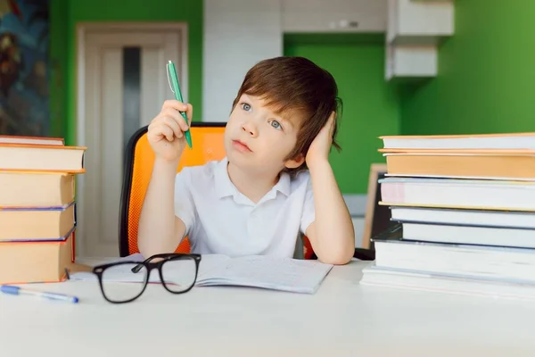 The boy is studying at home during CoVid-19 quarantine, distance learning online with a laptop, the child is doing homework for school. The schoolboy stayed at home.