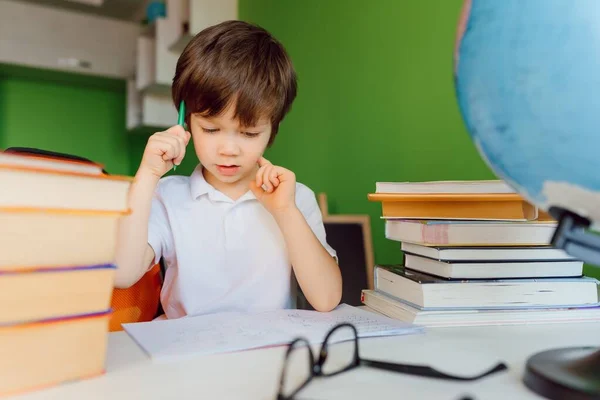 Stay at home, online learning, distance learning, self quarantine concept. Boy start doing homework with books notebooks for lesson at home