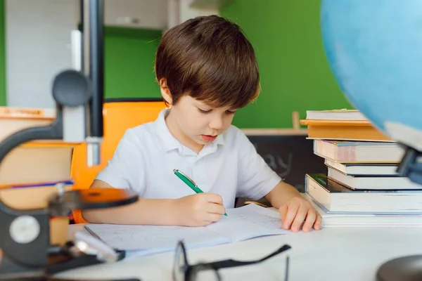 Stay at home, online learning, distance learning, self quarantine concept. Boy start doing homework with books notebooks for lesson at home