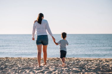 Anne ve oğlu gün batımında plajda oynuyorlar. Arkadaş canlısı aile kavramı.