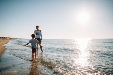 Anne ve oğlu gün batımında plajda oynuyorlar. Arkadaş canlısı aile kavramı.