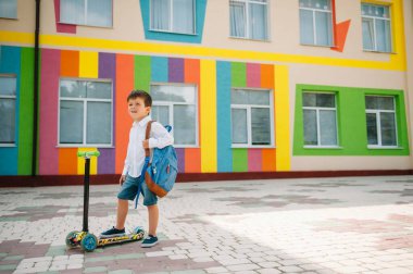 Oğlan okula motosikletle gidiyor. Çocuklar okula geri dönüyor. Scooter 'a binen çocuklar. Okula dönelim. Mutlu çocuklar. Mutlu çocukluk hayatı. Öğrenci okula gidiyor.