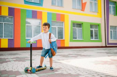Oğlan okula motosikletle gidiyor. Çocuklar okula geri dönüyor. Scooter 'a binen çocuklar. Okula dönelim. Mutlu çocuklar. Mutlu çocukluk hayatı. Öğrenci okula gidiyor.