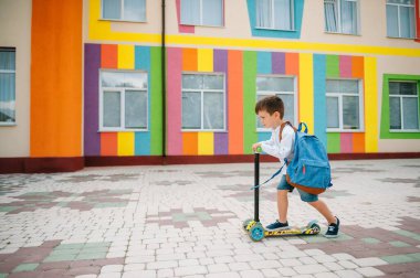 Oğlan okula motosikletle gidiyor. Çocuklar okula geri dönüyor. Scooter 'a binen çocuklar. Okula dönelim. Mutlu çocuklar. Mutlu çocukluk hayatı. Öğrenci okula gidiyor.